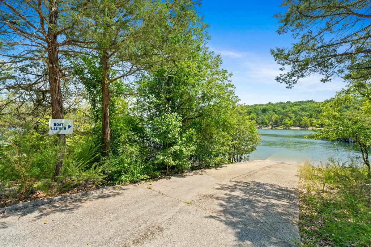 This serene scene features a boat launch area with a sloped path leading to calm lake waters, surrounded by lush greenery. The area is tranquil and accessible, inviting guests to enjoy boating, fishing, or lakeside walks.