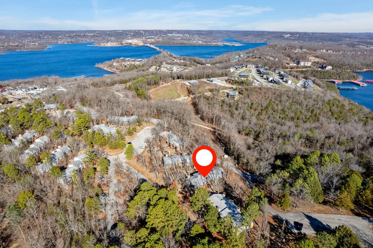 A broad view over Table Rock Lake, framed by surrounding forest and a glimpse of nearby residential areas. The scene emphasizes the natural beauty of the lake, plenty of space for boating or fishing, and opportunities to spot wildlife or stargaze during peaceful evenings.