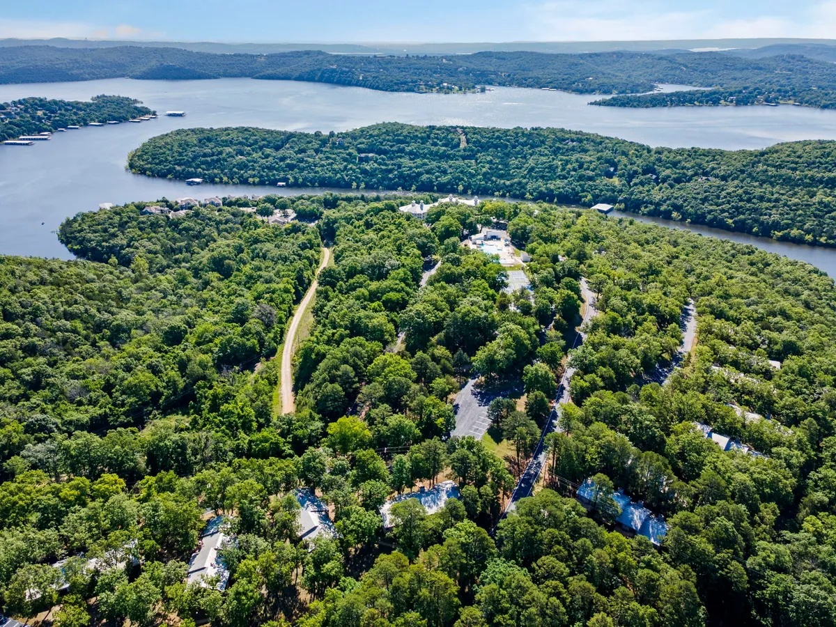 A wide, tranquil view of lush greenery, a serene water body, and a winding road leading through the residential area. The image showcases the expansive natural surroundings and opportunities for exploring on foot.
